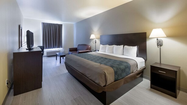 A modern hotel room with a large bed, bedside lamps, a desk, and a TV. - Econo Lodge Inn & Suites Bridgeport (Bridgeport)
