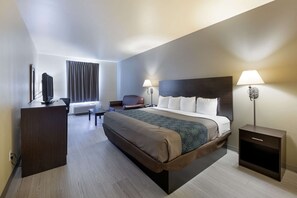 A modern hotel room with a large bed, bedside lamps, a desk, and a TV.