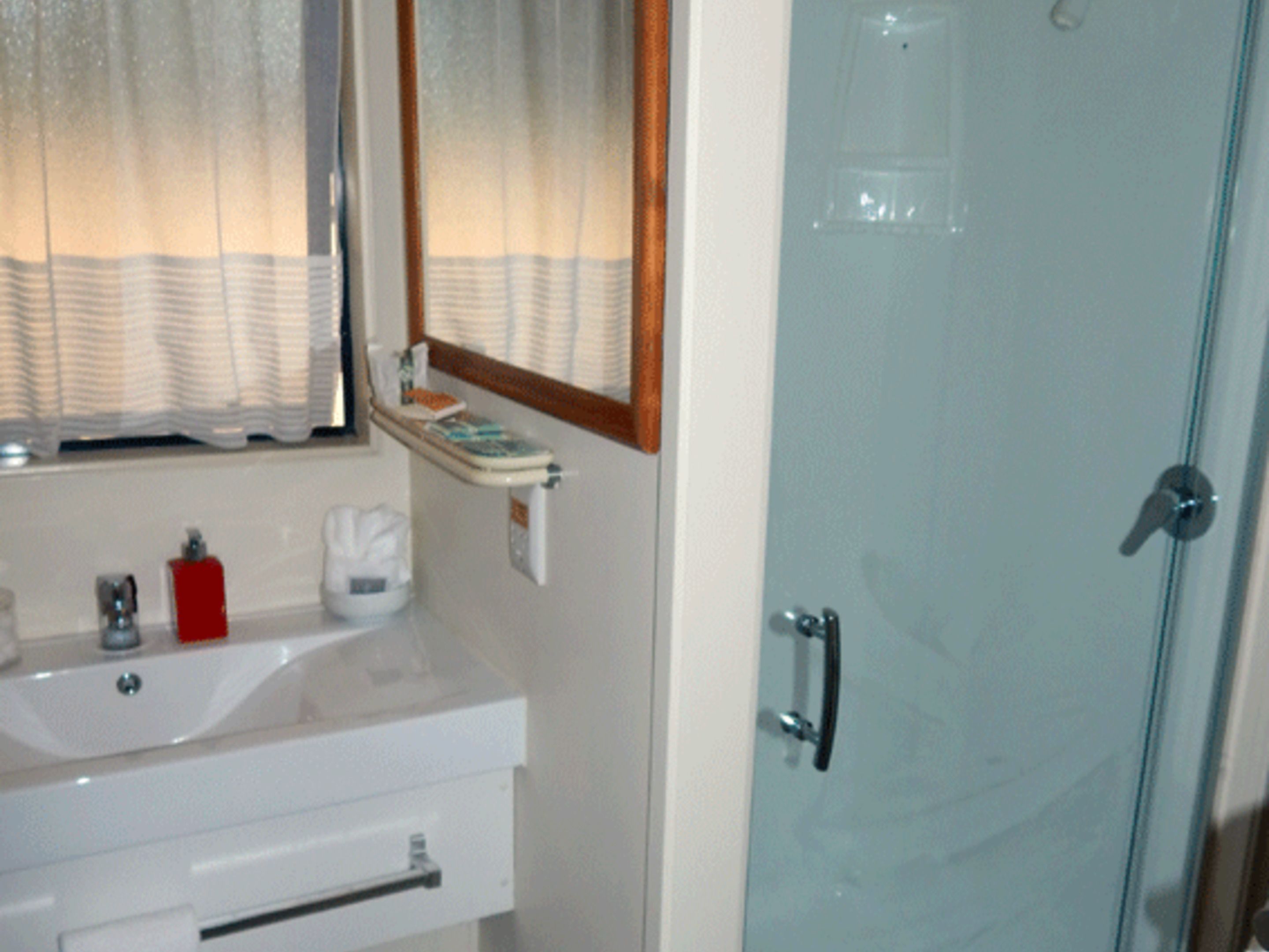 Un baño con lavabo, espejo y puerta de ducha de vidrio.