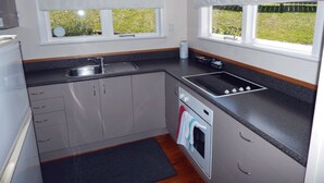 A kitchen with a sink, stove, oven, and cabinets. - Cheviot Park Motor Lodge (Whangarei)