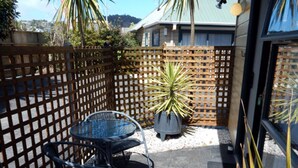 A patio area with a wooden lattice fence, a metal table with chairs, and a potted plant. - Cheviot Park Motor Lodge (Whangarei)