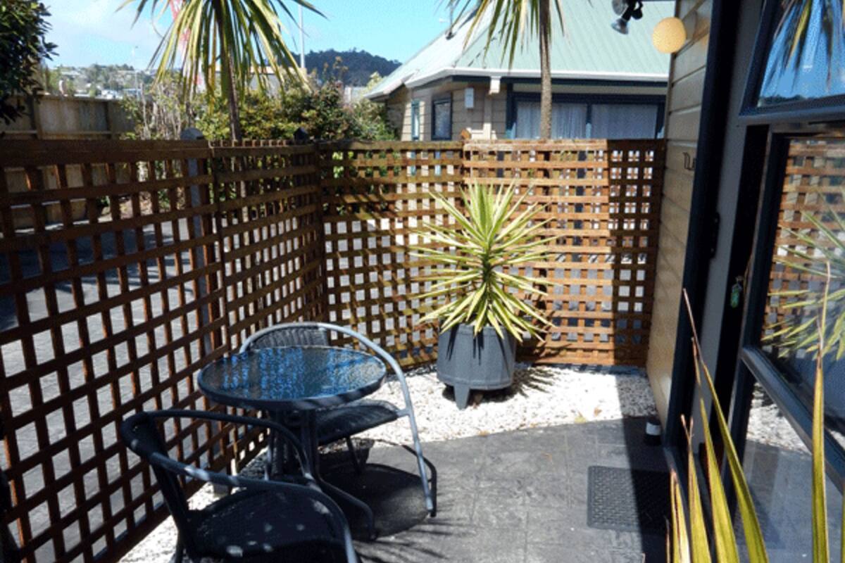 A patio area with a wooden lattice fence, a metal table with chairs, and a potted plant.