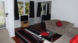 A living room with a sofa, a coffee table, a television, and a radiator. - Cheviot Park Motor Lodge (Whangarei)