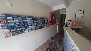 Un pasillo con un expositor de folletos turísticos y piso alfombrado.