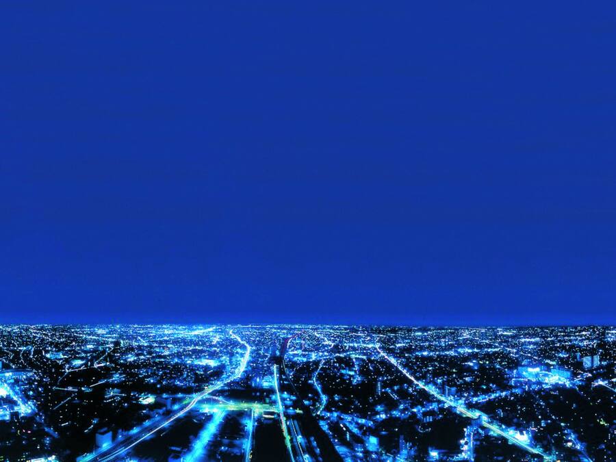 A cityscape at night with illuminated roads and buildings.