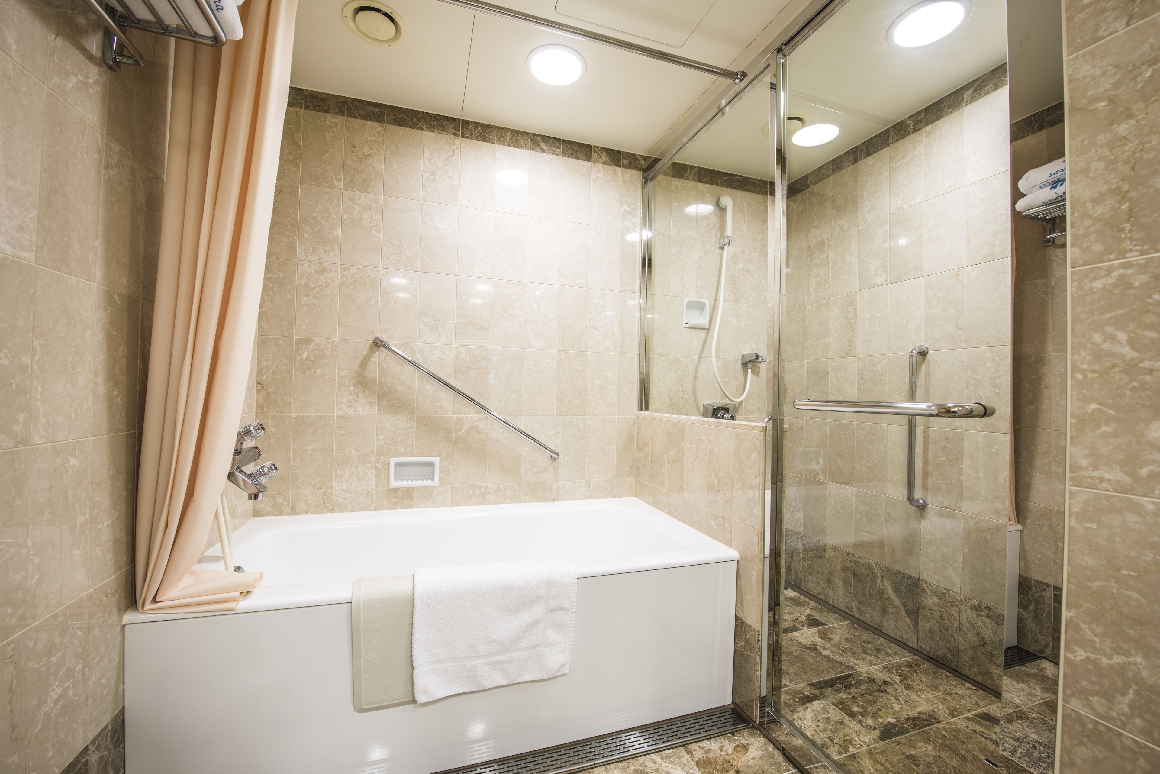 A modern bathroom with a bathtub, shower, and glass-enclosed shower area.