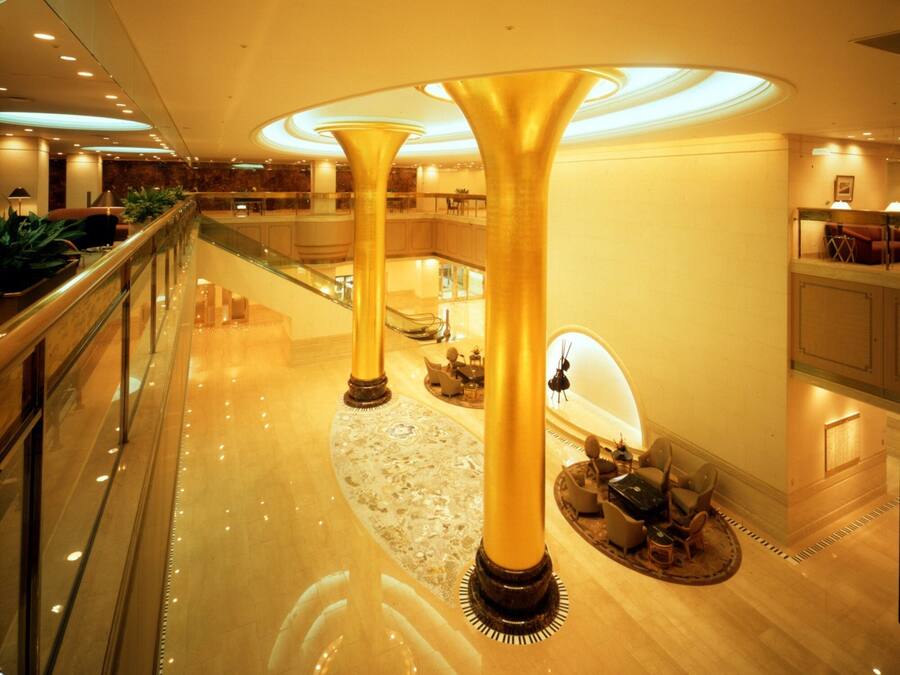 A spacious lobby with a high ceiling, a central column, and a staircase leading to an upper level.