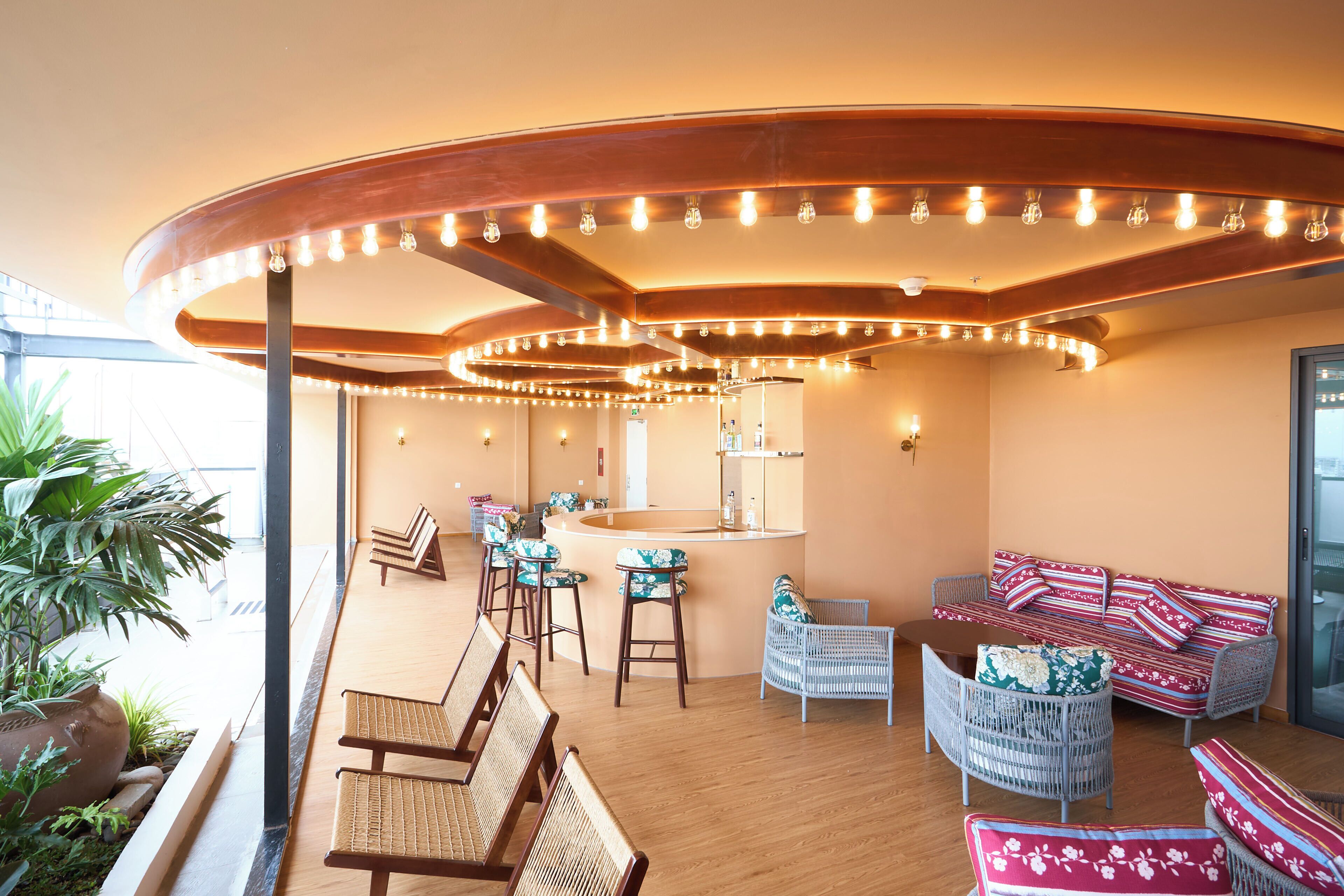 A modern interior with a curved ceiling, bar area, seating, and a large window.