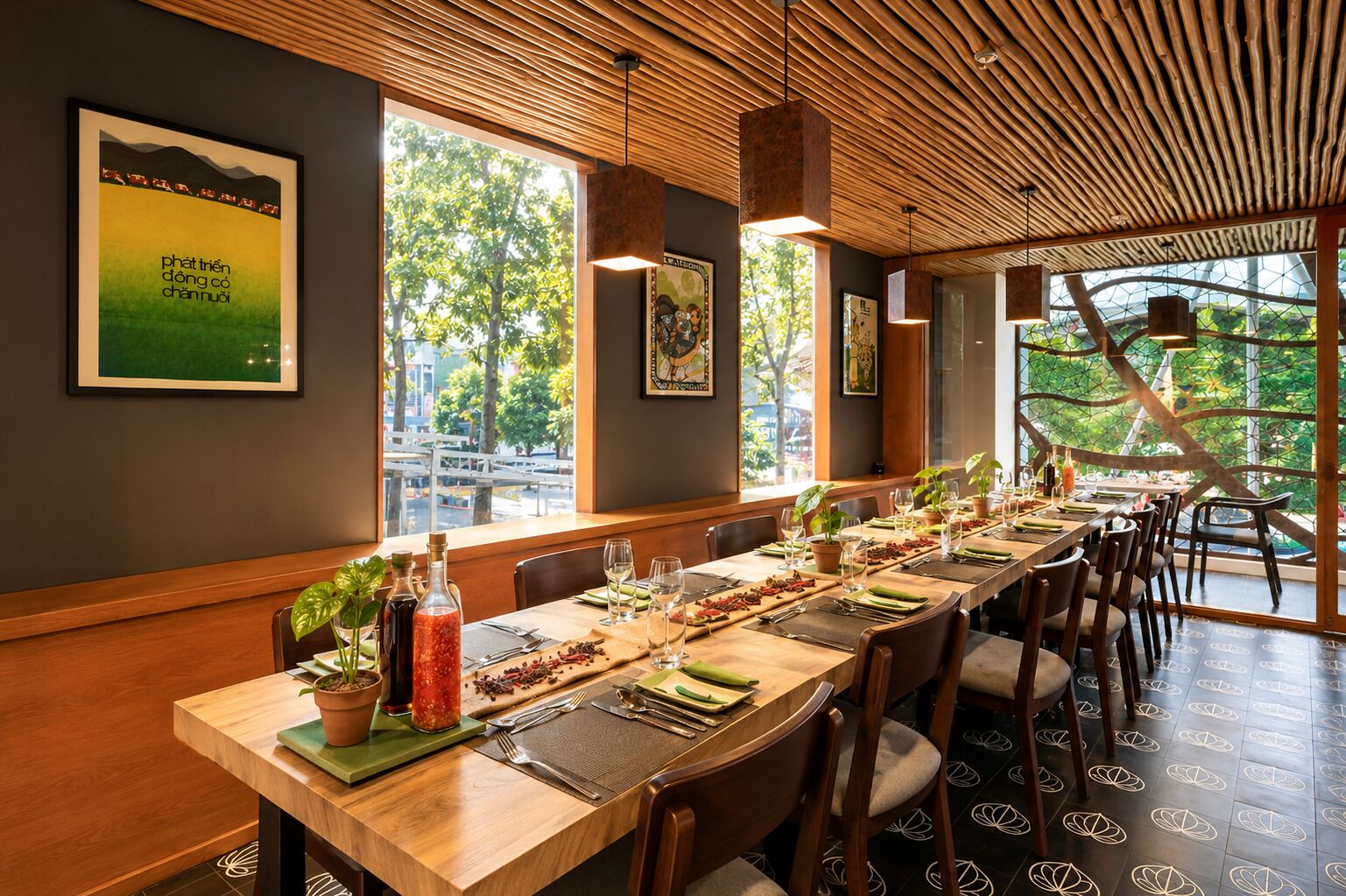 Un ristorante con un lungo tavolo di legno apparecchiato per la cena, ampie finestre che si affacciano su alberi e un soffitto in legno.