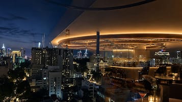Un hotel moderno con bar en la azotea, vistas a la ciudad y un diseño arquitectónico circular singular.