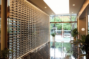 A lobby with a brick wall, a glass door leading outside, and a shiny floor. - G8 Center Hotel Saigon (Ho Chi Minh City)