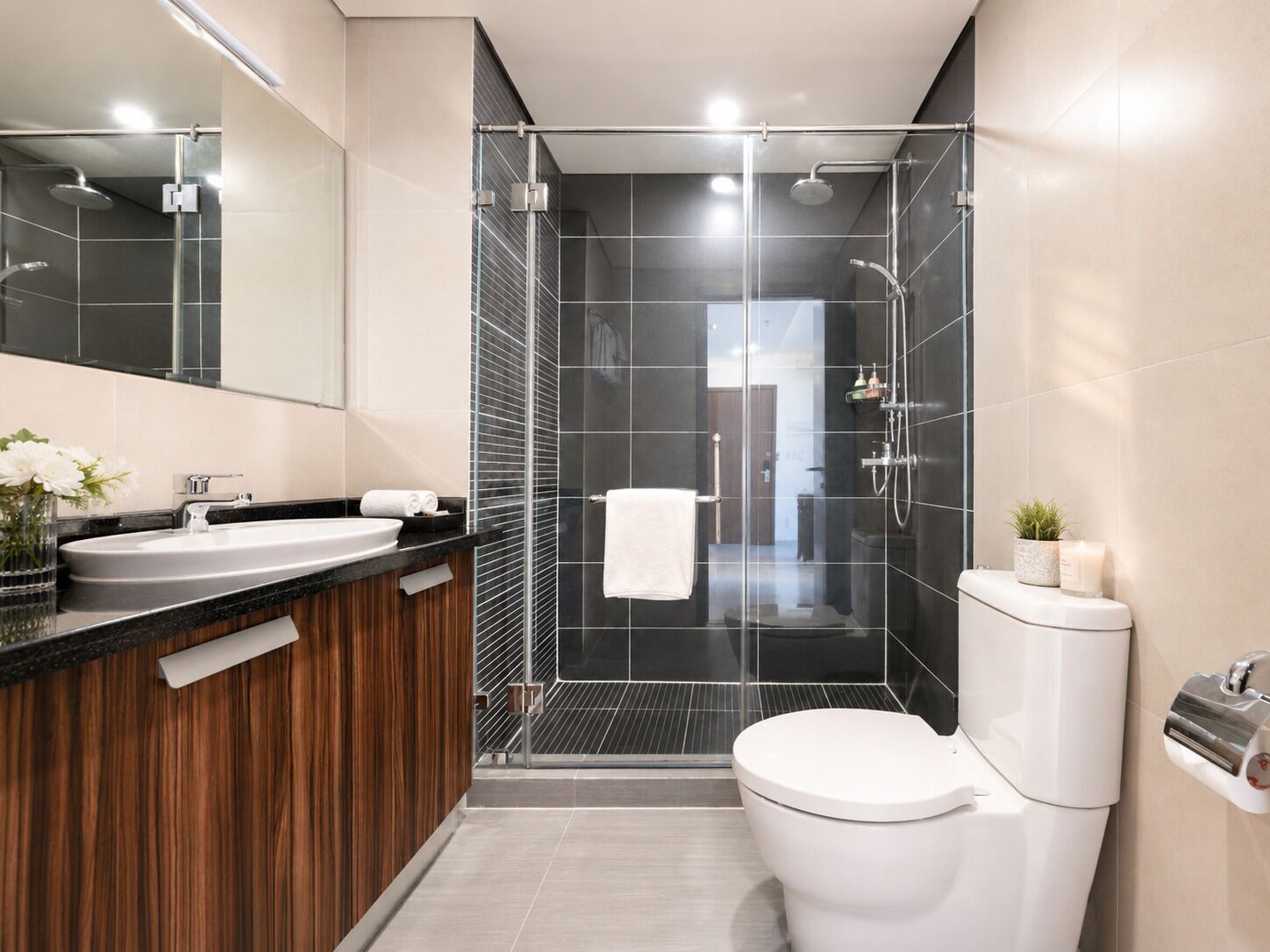 Un baño moderno con ducha envuelta en vidrio, inodoro blanco y tocador con espejo.