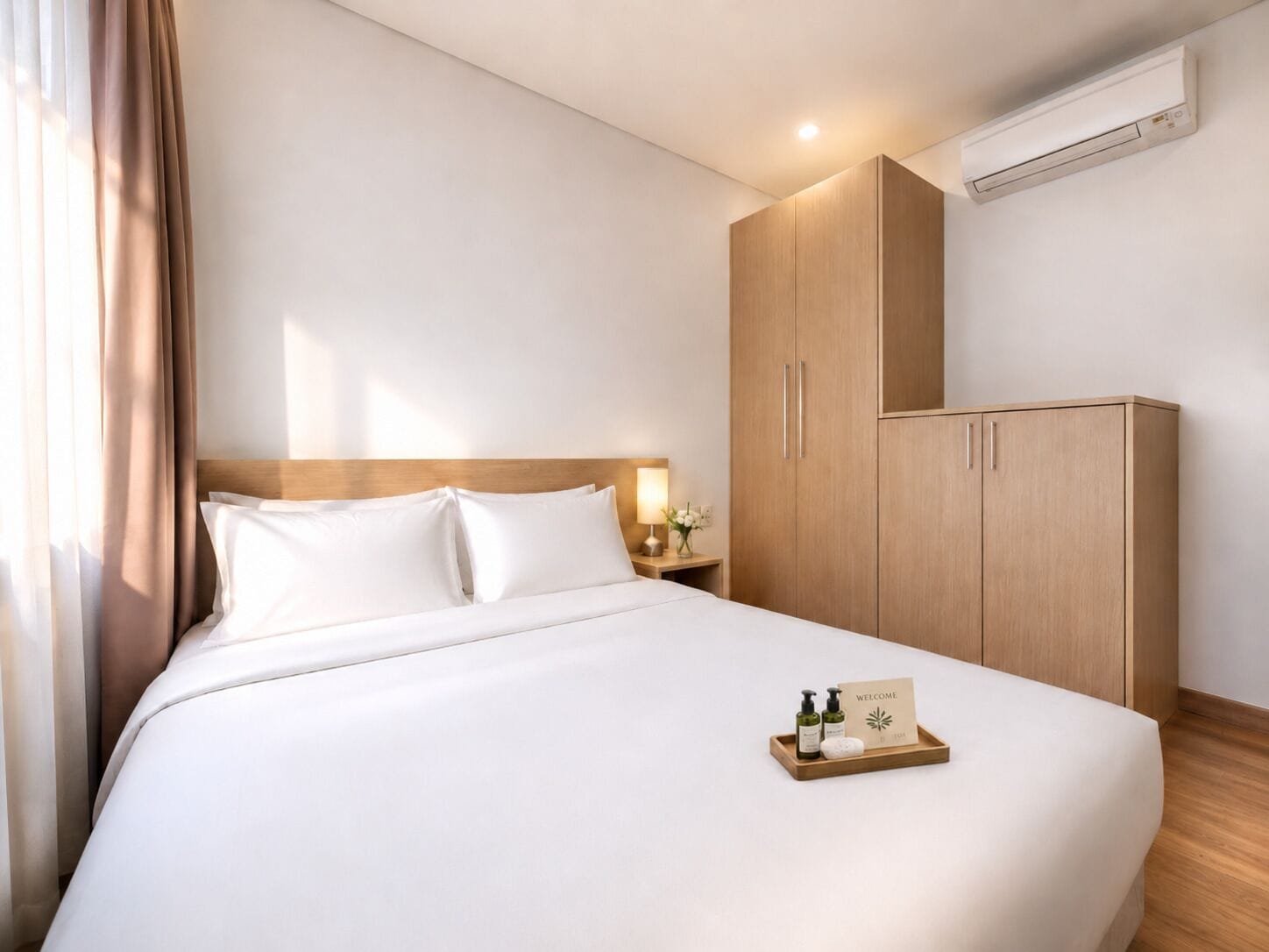 A hotel room with a bed, wooden wardrobe, and an air conditioning unit.