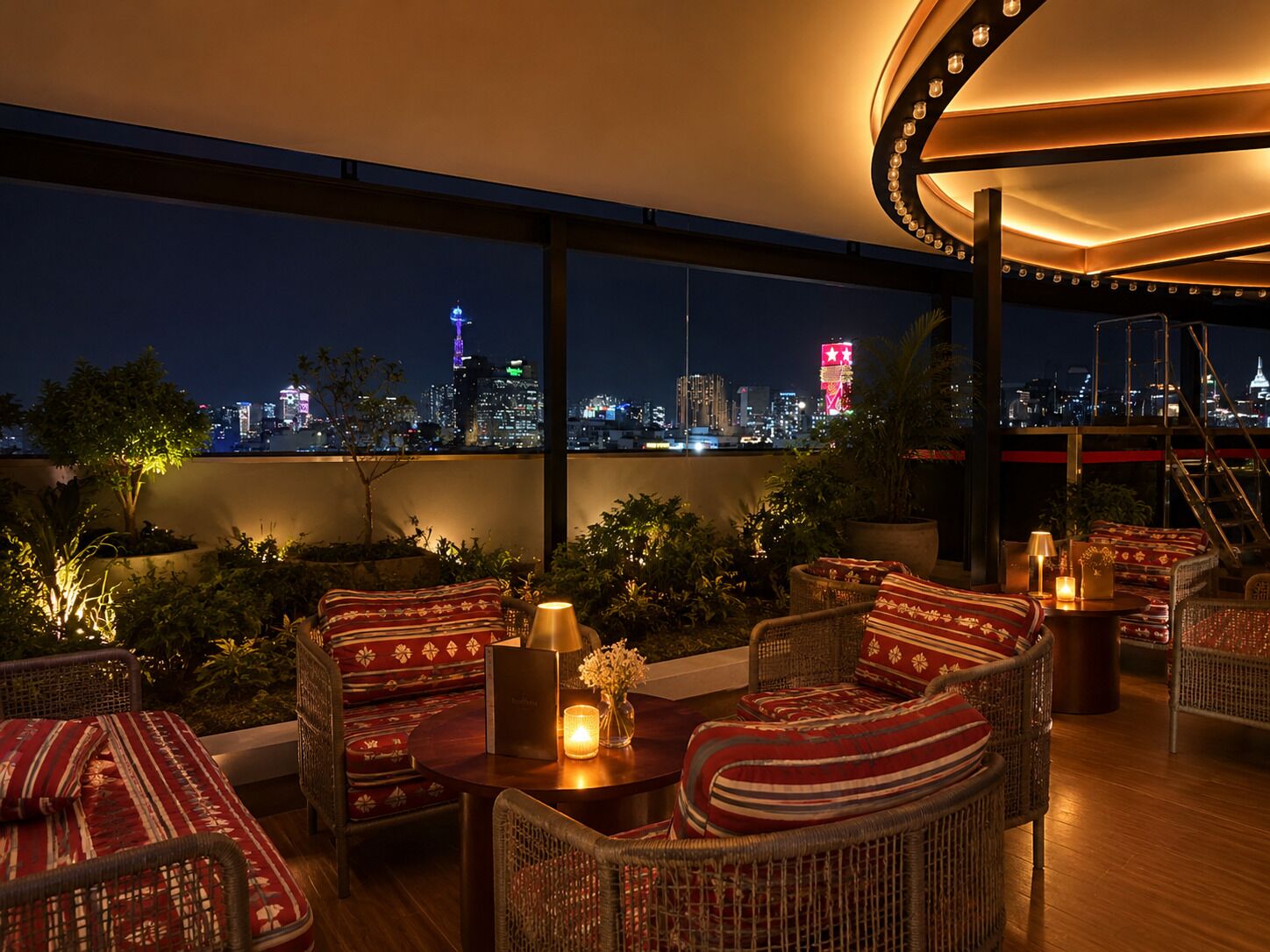 A rooftop lounge with wicker furniture, a view of a city skyline at night, and a large window.