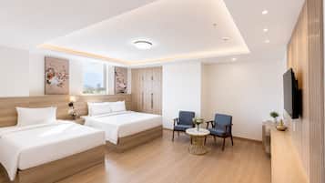 A hotel room with two beds, a seating area with chairs, a small table, and a TV mounted on the wall.