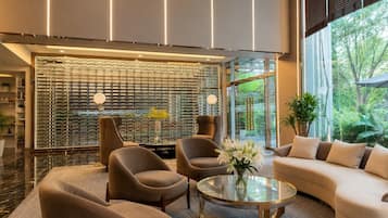 A modern interior with a glass partition, seating area, and a view of greenery.
