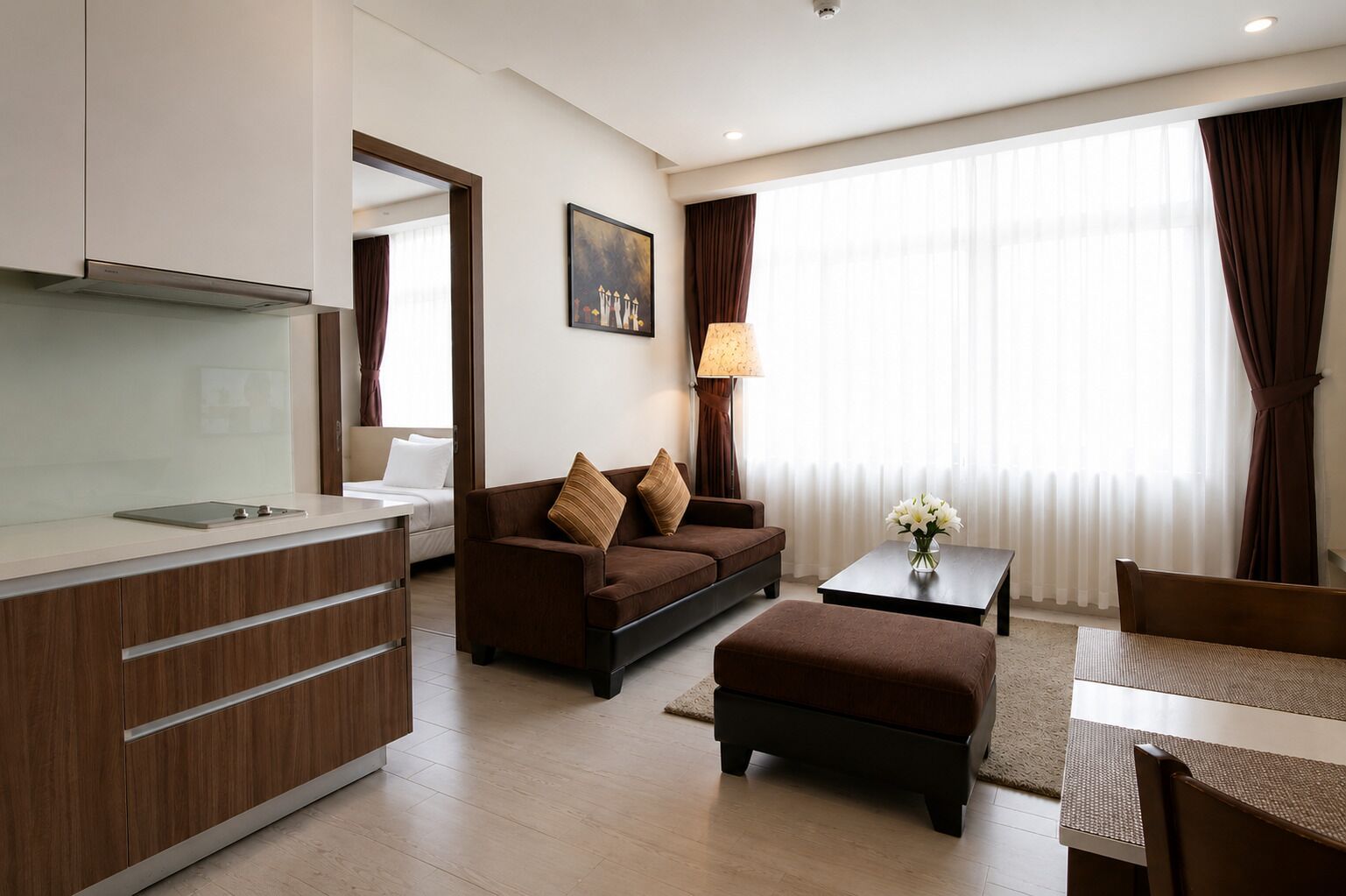 A modern hotel room with a kitchenette, a sofa, a coffee table, and a dining area.