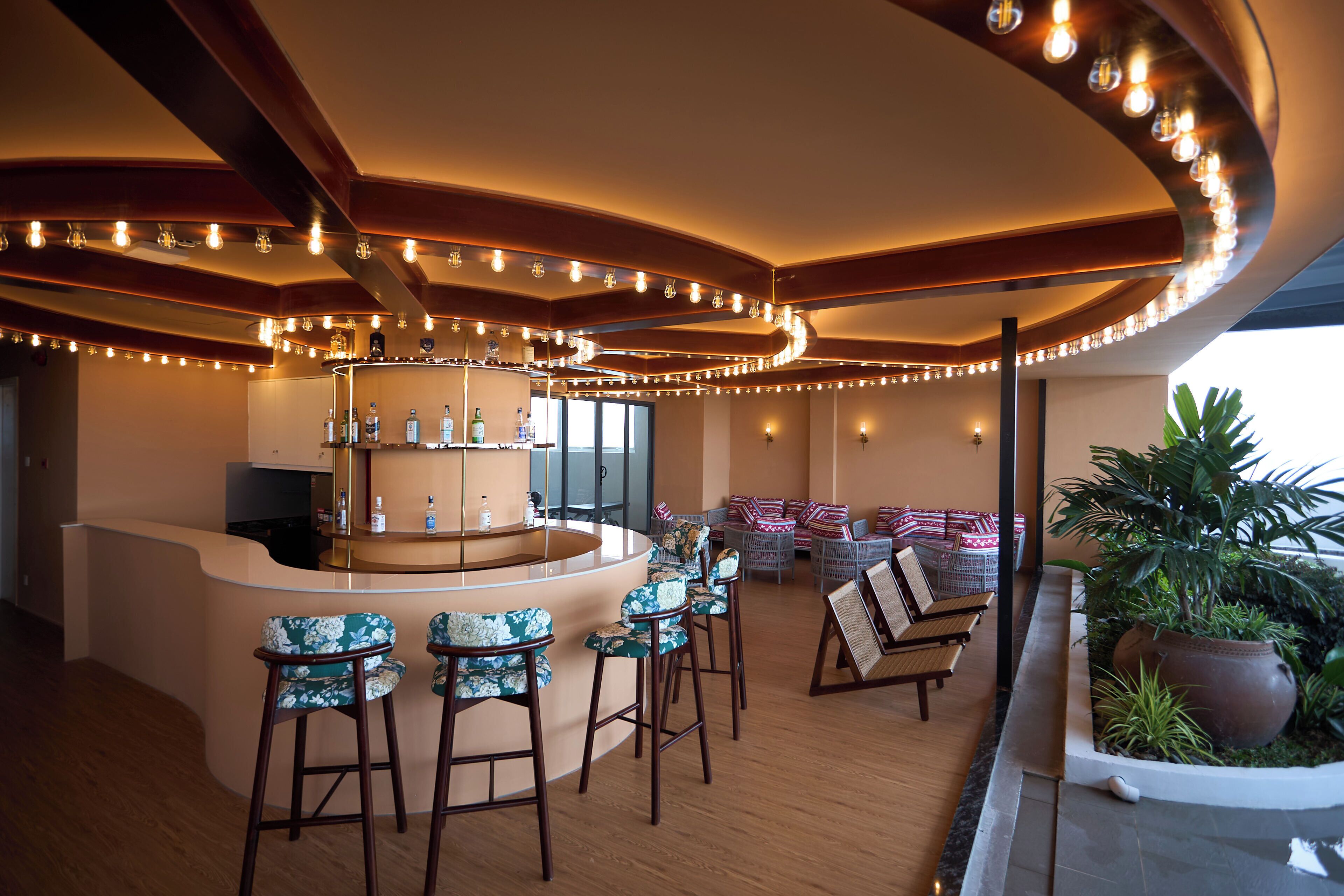 A bar area with a curved counter, bar stools, and a seating area with a sofa and chairs.