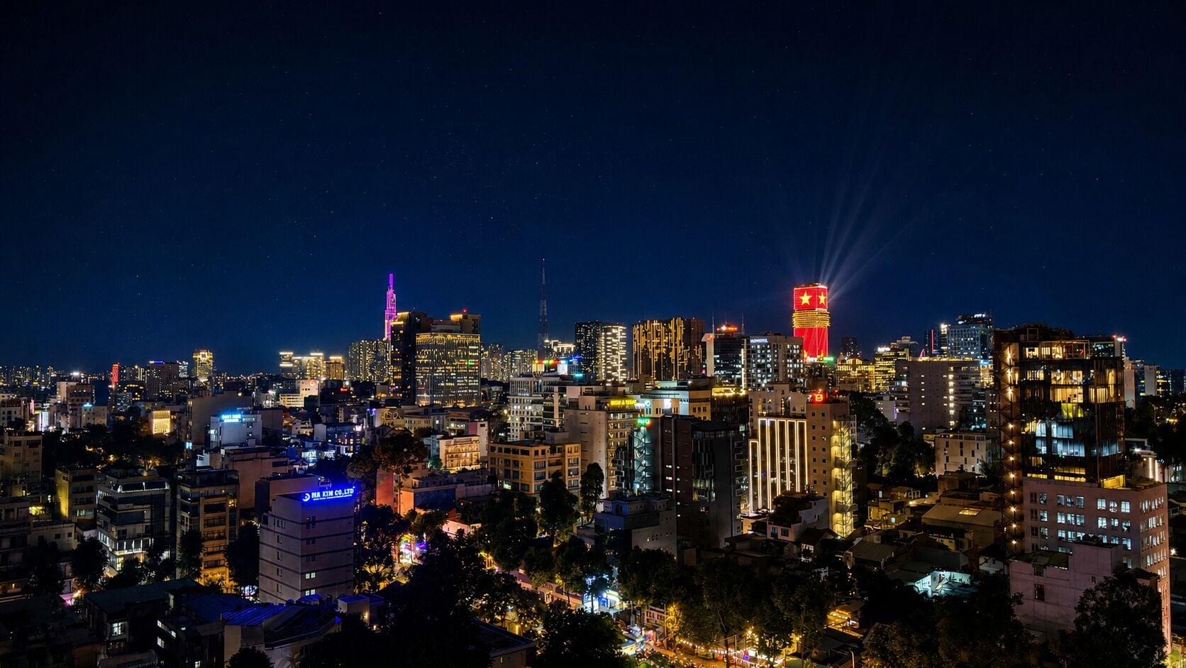 A cityscape at night with illuminated buildings and a prominent red star on a tower.