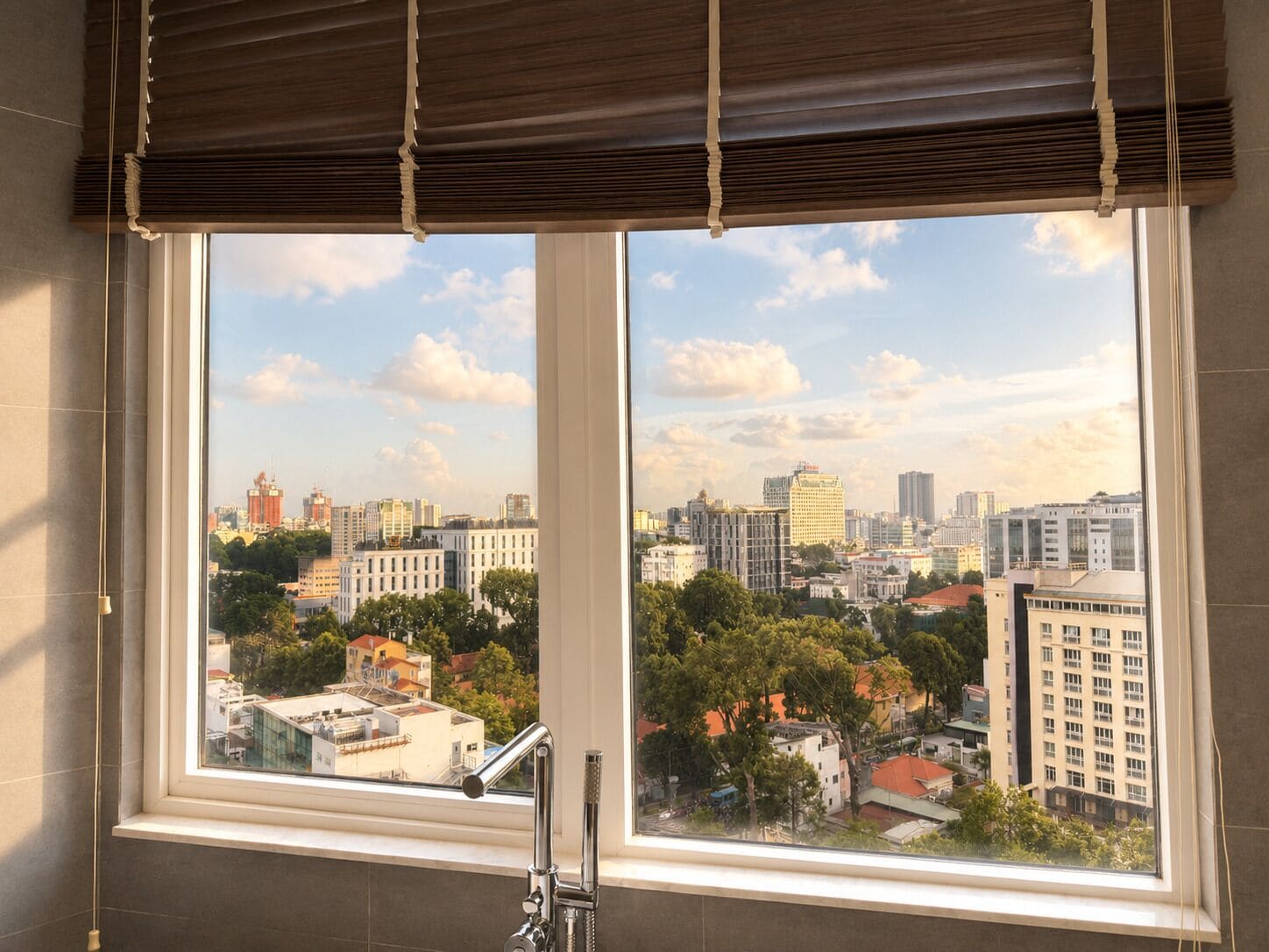 A bathroom with a large window, a modern faucet, and a view of a cityscape.