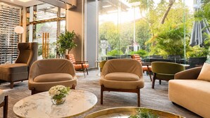 A modern lounge area with leather sofas, a marble coffee table, and large windows overlooking a garden. - G8 Center Hotel Saigon (Ho Chi Minh City)
