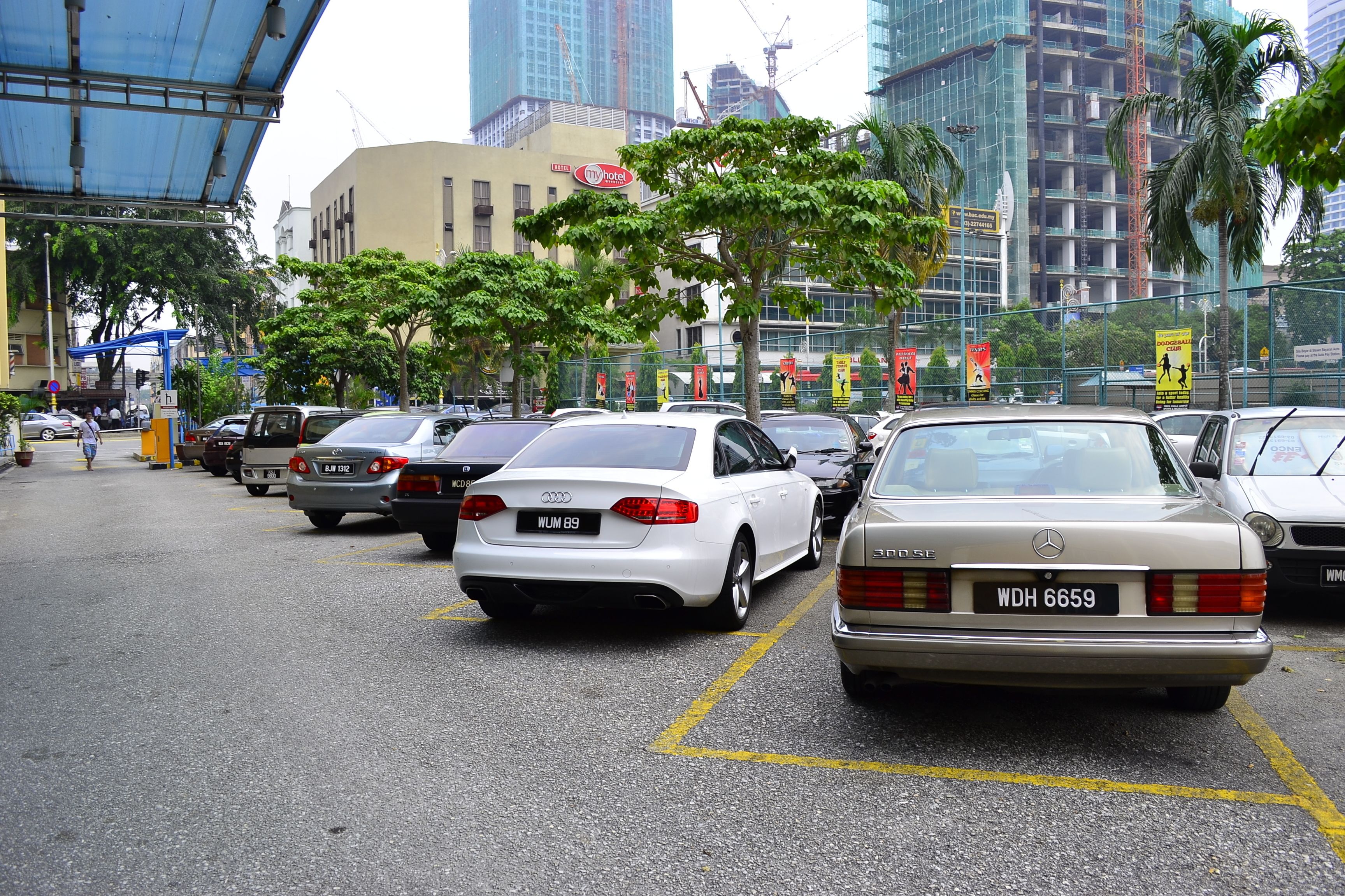 A parking lot with several cars, including a white Audi and a beige Mercedes-Benz.
