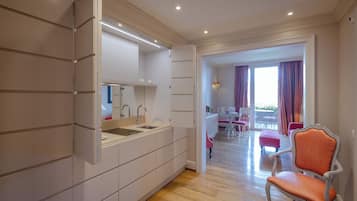 A modern kitchen with integrated appliances, a dining area with a table and chairs, and a balcony with curtains.