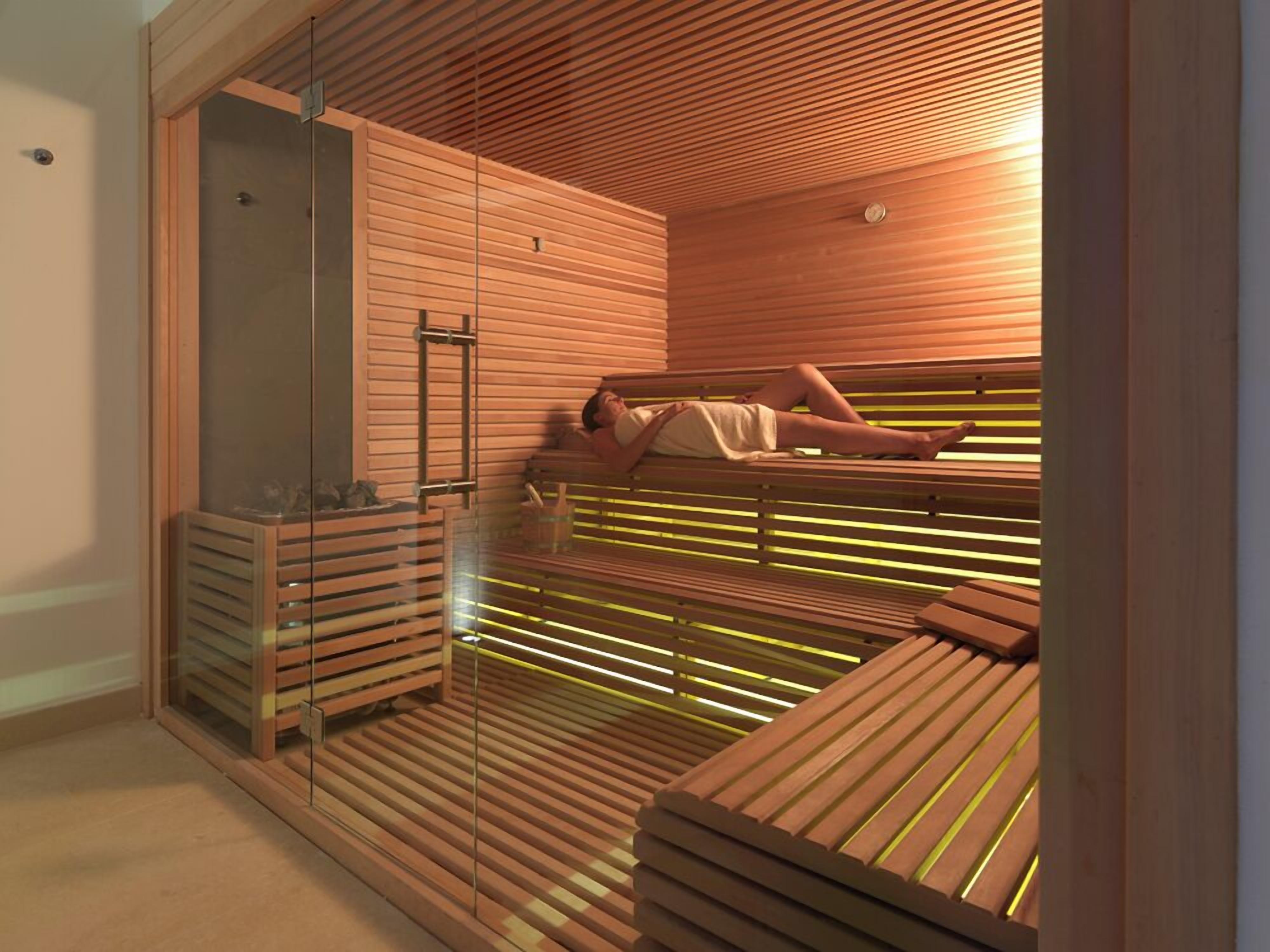 Una sauna con bancos de madera y puerta de cristal.
