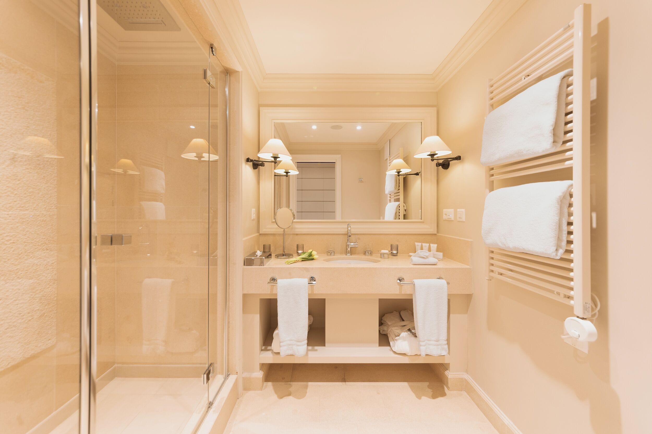 Un baño moderno con cabina de ducha de vidrio, tocador doble y perchero.