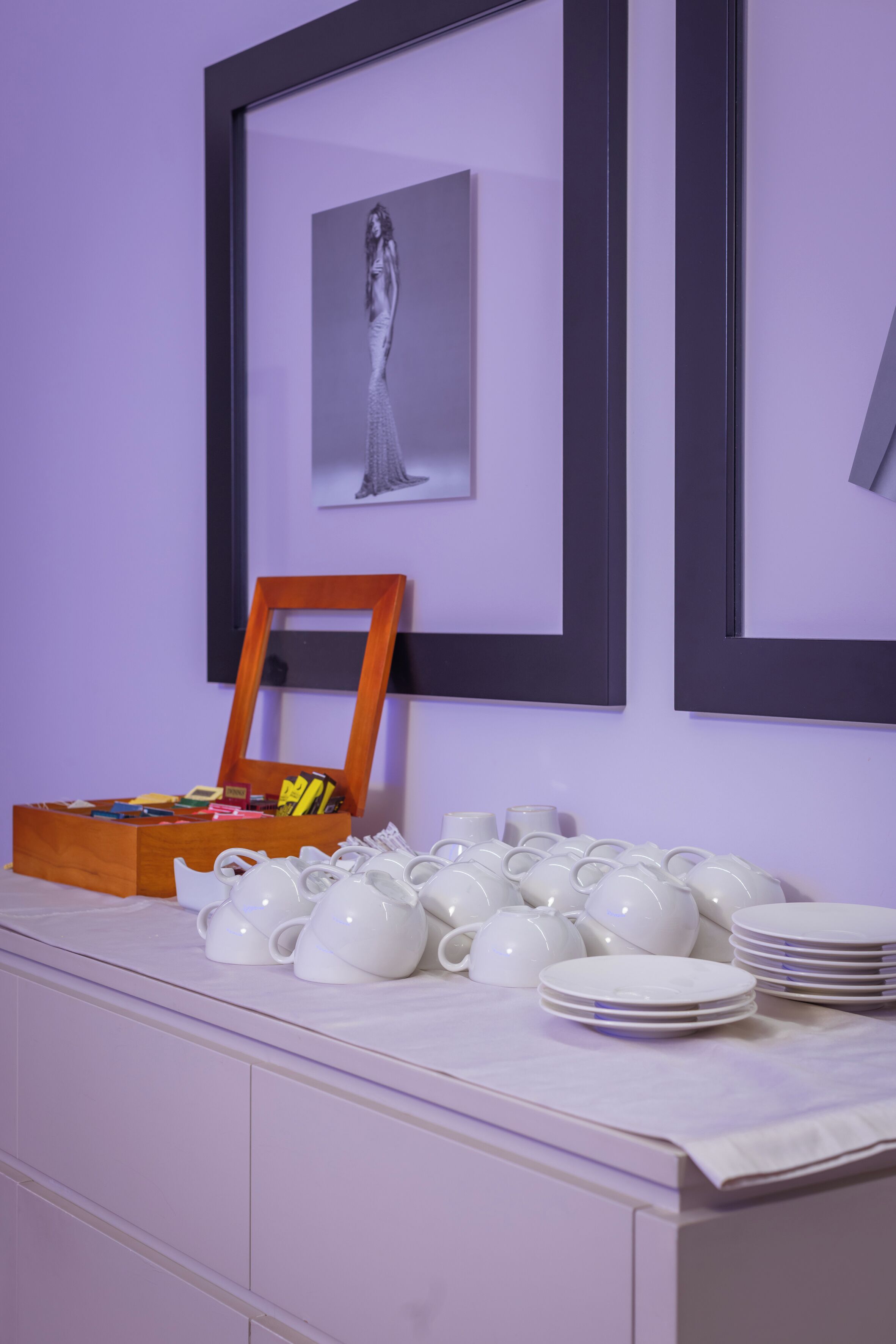 A room with a white cabinet, a wooden box with stationery, and white teapots and plates on a table.