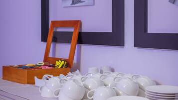 A room with a white cabinet, a wooden box with stationery, and white teapots and plates on a table.