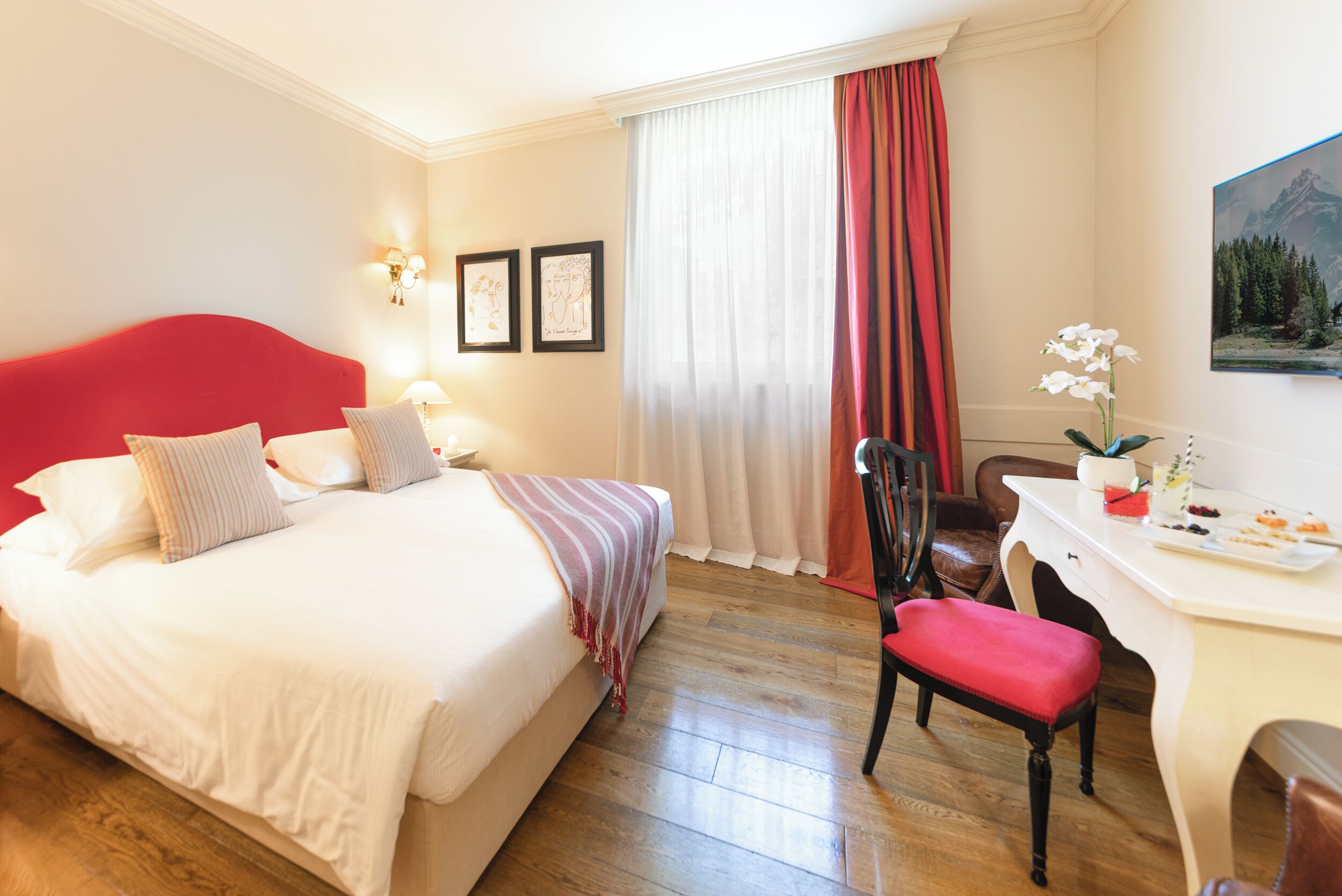Ein Hotelzimmer mit einem großen Bett, einem Schreibtisch, einem Stuhl und einer Schreibtischlampe.