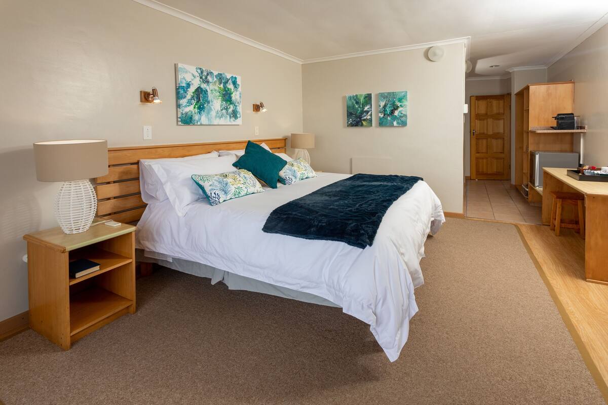 A neatly arranged bedroom with a bed, bedside tables, and a desk.