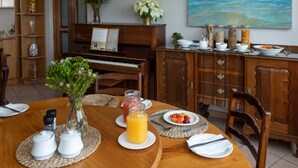 A dining table set with plates, cutlery, and a pitcher of orange juice. - Aire del Mar Guest House (Kleinbaai)