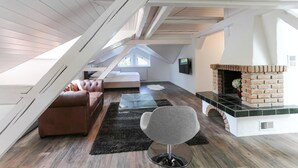 Et loftrum med pejs, lædersofa og en moderne stol.