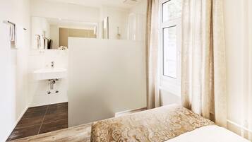 Un dormitorio moderno con una cama grande, tocador empotrado y zona de ducha.