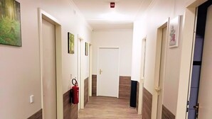 A hallway with wooden flooring, white walls, and doors on both sides. - Pension Puschkin Berlin (Berlin)