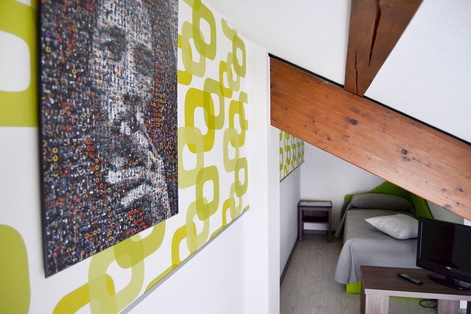 Una stanza con un letto, una televisione e una parete decorata con un'opera d'arte astratta di grandi dimensioni.