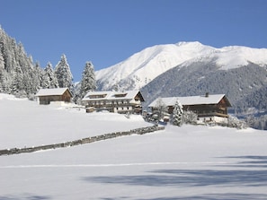 A snow-covered mountain landscape with wooden cabins and a wooden fence.