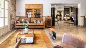 Un salon spacieux avec un canapé en cuir, une table basse en verre et un coin repas à l’arrière-plan.