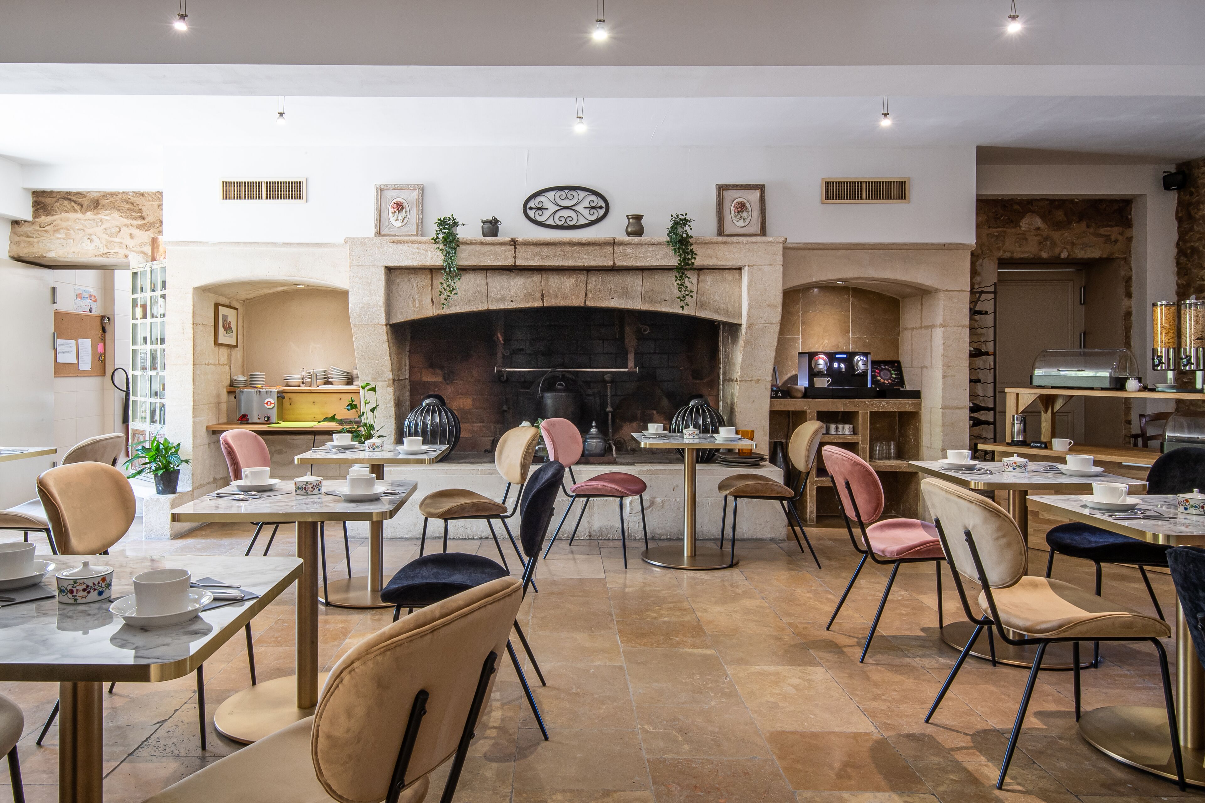 A dining area with multiple tables and chairs, a fireplace, and various kitchen appliances.
