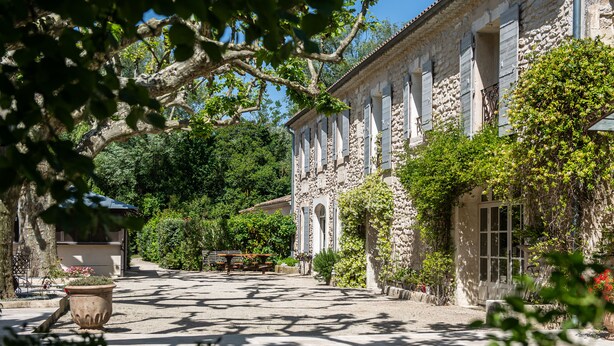 Un bâtiment en pierre doté de fenêtres en arc de cercle et d’un patio couvert.