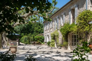 A stone building with arched windows and a covered patio area. - Mas Valentine Hôtel (St.-Rémy-de-Provence)