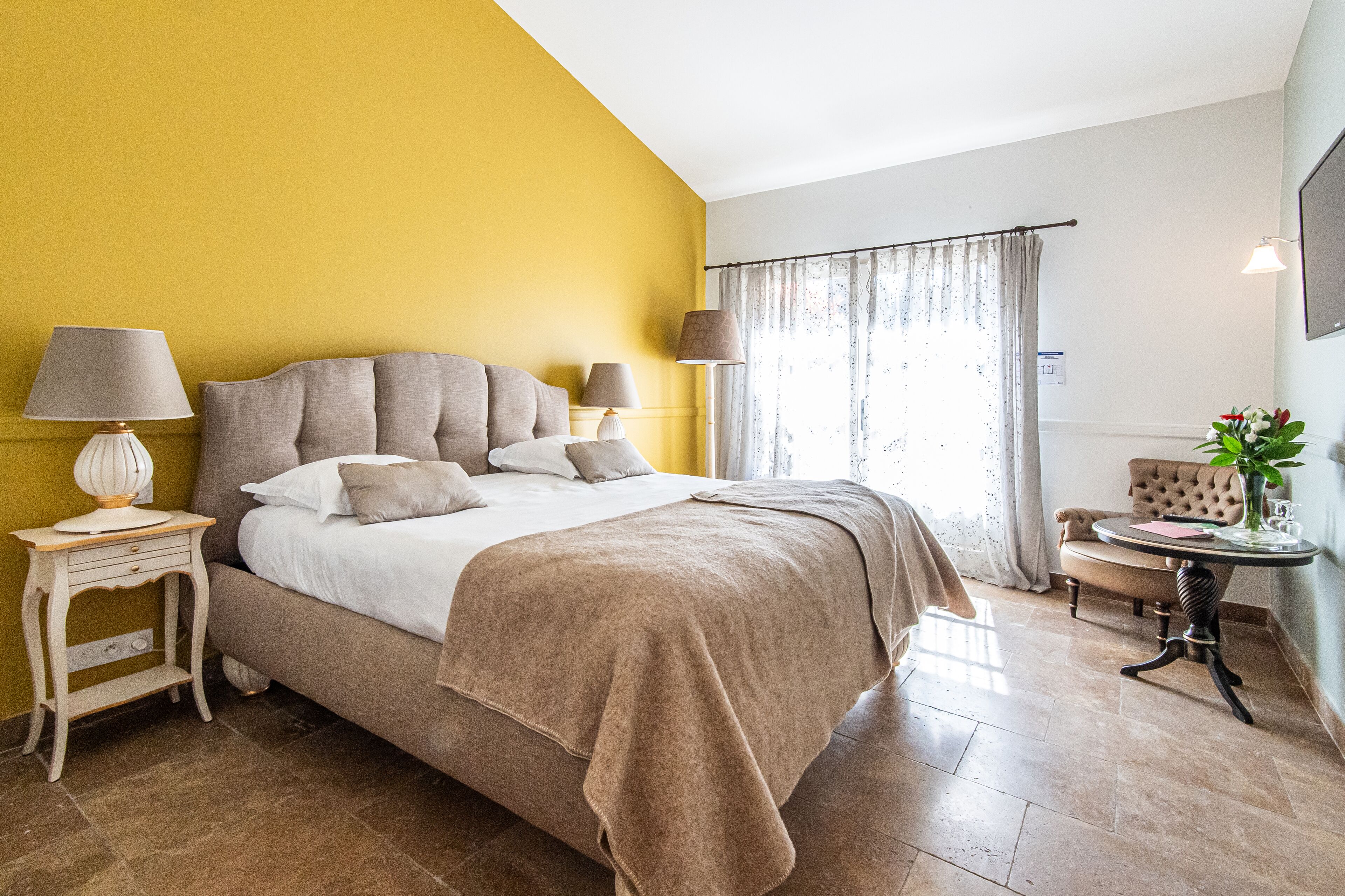 A bedroom with a bed, bedside tables, a chair, and a window with curtains.