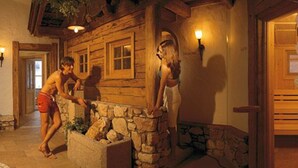 A rustic wooden cabin interior with stone walls, a stone bench, and a towel rack. - Hotel Sportalm (Gerlos)
