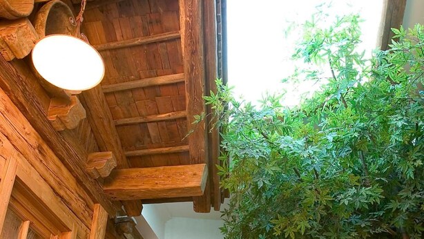 A rustic wooden building with a stone staircase, a wooden door, and a wall-mounted towel rack. - Hotel Sportalm (Gerlos)