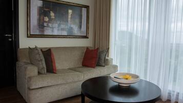 A living room with a beige sofa, a black coffee table, and a framed abstract painting on the wall.