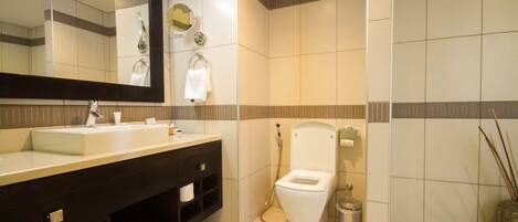 Un baño moderno con un espejo grande, un lavamanos blanco, un inodoro y un cubo de basura.
