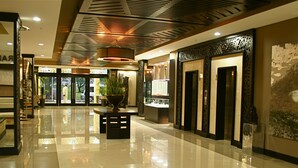 A hotel lobby with a polished floor, a reception desk, a large potted plant, and a wall-mounted artwork. - Mount Meru Hotel (Arusha)