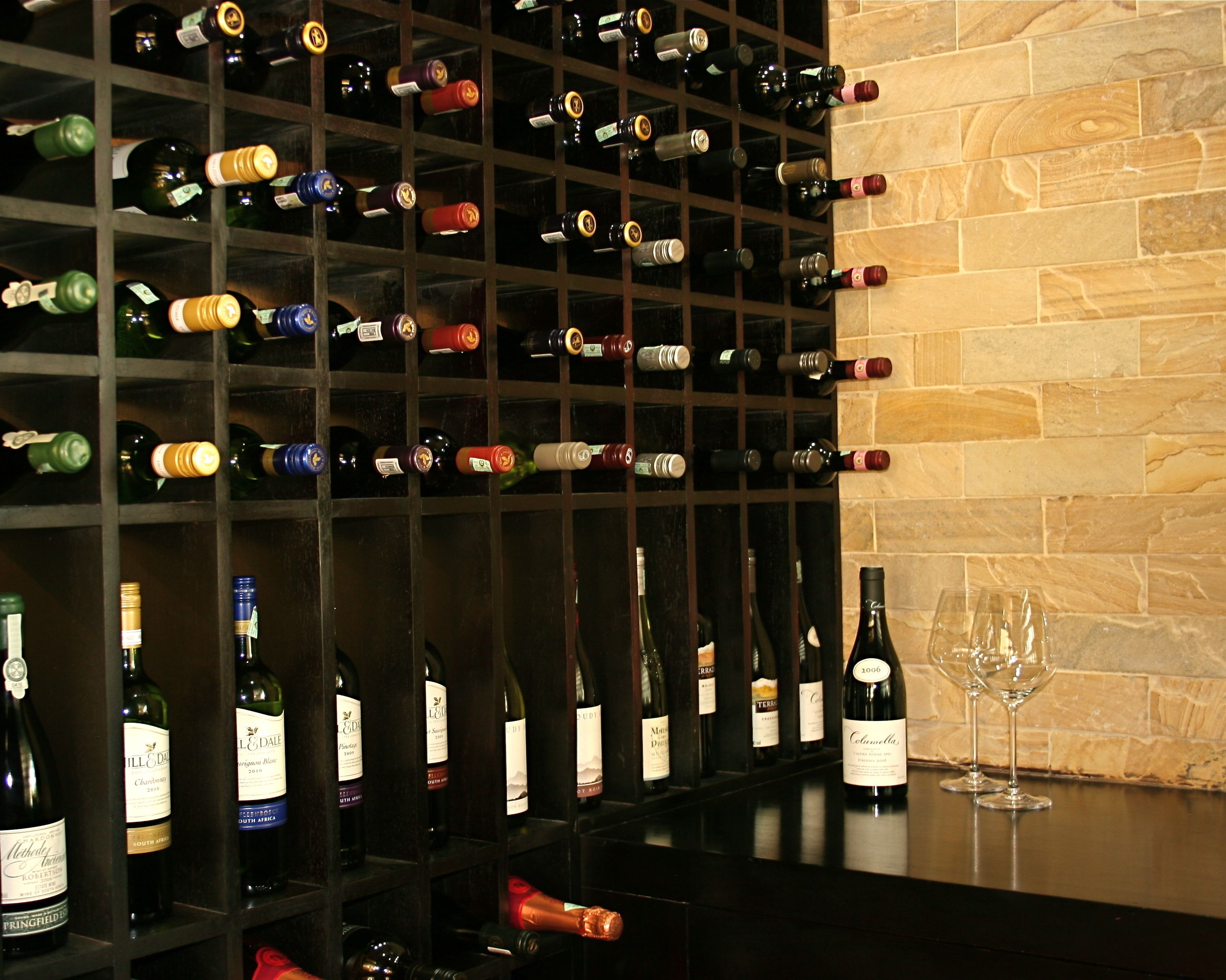 A wine rack with various bottles and a wine glass on a counter.
